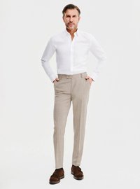 Biała koszula zapinana na guziki, jasnobeżowe spodnie w kratę oraz brązowe zamszowe buty. Spodnie mają dopasowany krój i gładki przód.