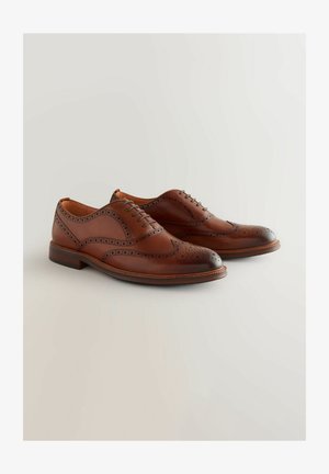 Brązowe skórzane buty brogues z okrągłym noskiem, wiązanym fasonem, skomplikowanymi perforacjami oraz kontrastującą ciemną nasadą. Gładka faktura.