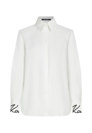 White long-sleeve shirt with a button-down collar, featuring a relaxed fit and black embroidered accent on the cuffs. Smooth texture.