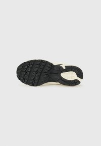 Suela de zapato de goma negra con un patrón de agarre texturizado. Presenta una entresuela de color crema, un diseño curvado y un logotipo de marca en relieve.