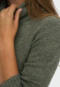 Pullover in maglia di un verde oliva tenue, con colletto alto e polsini a costine, realizzato in un tessuto morbido e strutturato.