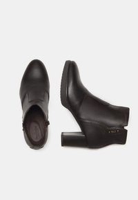 Black leather ankle boots with a smooth texture, rounded toe, side zipper, and chunky block heel, featuring minimal stitching and brand detail.