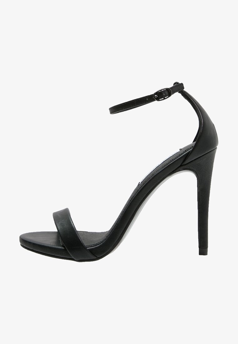 Sandale noire à talon haut avec fine bride à la cheville et boucle, bout ouvert, et une seule bride avant, vue de côté sur fond blanc.