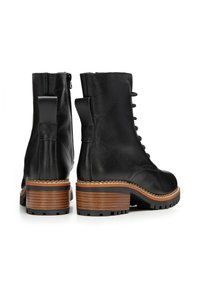 Stivali ankle in pelle nera con punta arrotondata, lacci anteriori e zip sul retro. Tacco a blocco spesso e strutturato marrone con accenti neri.