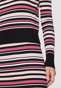 Robe à manches longues côtelée présentant des rayures horizontales en noir, rose et blanc. Comprend un accent de logo métallique près de l'ourlet.