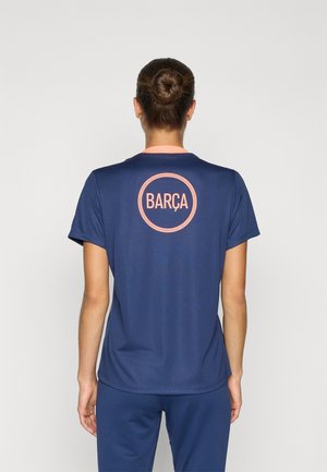 Marineblauw sportshirt met een slim fit, beschikt over een roze kraag en een cirkelvormig "BARÇA"-logo op de achterkant in contrasterende kleur. Glad stoftextuur.