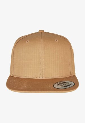 Casquette snapback beige avec un corps en tissu texturé, visière plate et un patch logo circulaire. Présente des détails de couture et des trous de ventilation.