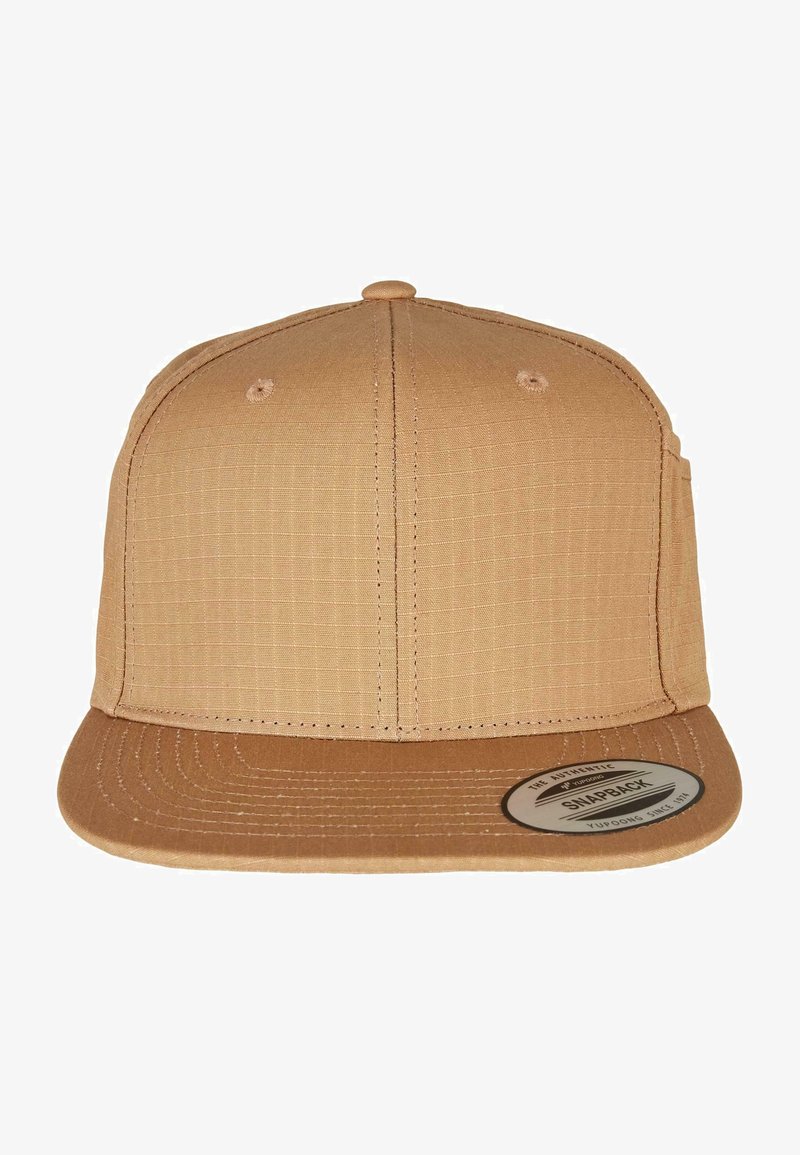 Tan snapback cap with a textured fabric body, flat brim, and a circular logo patch. Features stitching details and ventilation holes.
