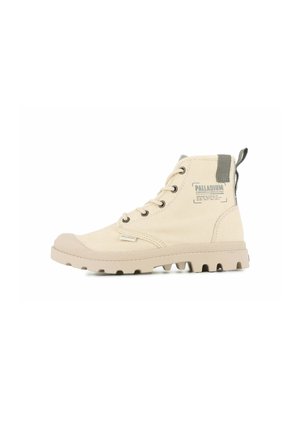 Bottines en toile beige avec une finition texturée, semelle en caoutchouc et onglet d'accent gris. Comprend des œillets en métal et un patch de marque sur le côté.