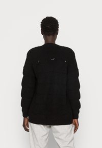 Maglione lavorato a maglia nera con un motivo testurizzato, scollo rotondo e maniche lunghe e voluminose. Adatto per una vestibilità comoda.