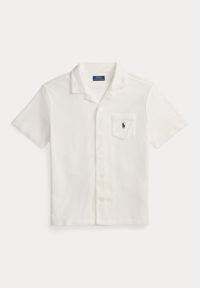 Άσπρο πόλο πουκάμισο με κοντά μανίκια από μαλακό ύφασμα, με κλασικό γιακά, κλείσιμο με κουμπιά και ένα τσέπη στο στήθος με μικρό κεντημένο λογότυπο.