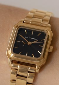 Goldfarbenes rechteckiges Armbanduhren mit einem schwarzen Zifferblatt, goldenen Stundenmarkierungen und einem einfachen Mondphasenanzeiger. Verfügt über ein verknüpftes Metallarmband.