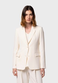 Blazer color crema con vestibilità su misura, rever a punta, due tasche frontali e chiusura con un solo bottone, realizzato in tessuto morbido.