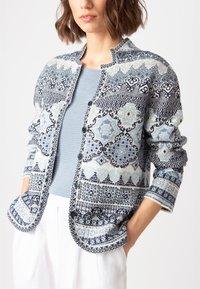 Zils rakstains kardigans ar sarežģītiem dizainiem tumši zilā un gaiši zilā krāsā. Ar priekšējiem pogām un atvērtām kabatām. Strukturēts audums, brīvi izgriezts.
