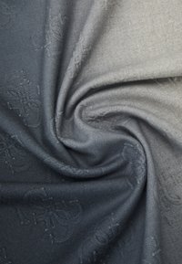 Tessuto grigio e blu navy con texture avvolto in una spirale, caratterizzato da un sottile motivo floreale e una finitura morbida e liscia.