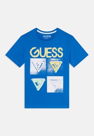 Plava pamučna majica s žutim logotipom "GUESS" i četiri reljefna dizajna trokuta u bijeloj, žutoj i zelenoj boji na prednjoj strani. Kratki rukavi.