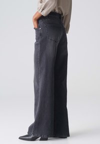 Schwarze Jeans mit weitem Bein aus Denim, hoher Taille, zwei Gesäßtaschen und leicht verwaschenem Finish.