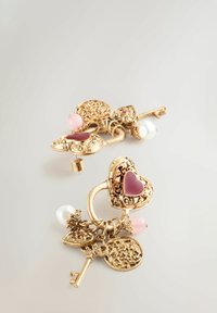 Goldfarbene Ohrringe mit kunstvollen, vintage-inspirierten Schlüssel- und Herzdesigns, verziert mit rosa Steinen und Perlen, die eine detaillierte Textur präsentieren.