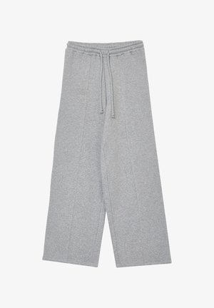 Pantaloni della tuta grigi, ampi e con elastico in vita e cordoncino regolabile. Tessuto morbido con cuciture a vista e senza tasche.