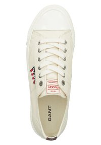 Zapatillas de lona en color blanco roto con puntera de goma, ojales de metal y etiqueta de marca. Presenta cordones blancos y suela texturizada.