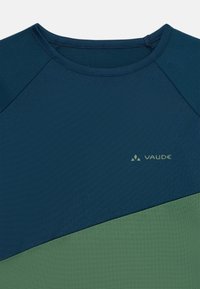 Camiseta atlética en azul y verde con una tela texturizada, que presenta un diseño de manga raglán y un pequeño logo impreso de "Vaude" en el pecho.
