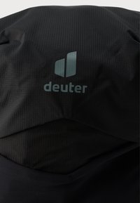 Rucsac Deuter din material textil negru cu un model texturat, având un logo subtil în albastru deschis. Suprafață netedă și durabilă cu un design structurat.