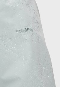 Helleblaue wasserdichte Stoff mit einer Textur aus Tropfen, versehen mit einem gestickten Logo in einer kontrastierenden Farbe. Glatte Oberfläche mit dezentem Glanz.