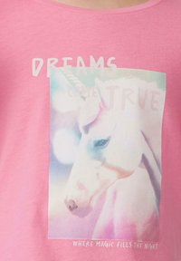 Rosa Baumwoll-T-Shirt mit einem Grafikdesign eines Einhorns und dem Text "TRÄUME WERDEN WAHR" sowie "WO MAGIE DIE NACHT FÜLLT" darunter.
