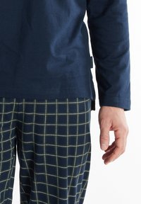 Navy long-sleeve shirt with a smooth texture, paired with checkered pajama pants in dark blue and green lines, featuring side slits.