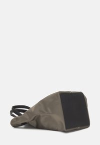 Borsa in tessuto khaki con una base nera quadrata. Design morbido e strutturato, con spallacci regolabili e chiusura con zip sulla parte superiore.