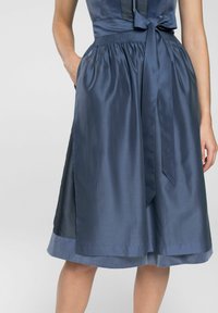 Marineblauwe jurk met een getailleerde top en een vloeiende rok. Heeft een gerimpelde taille, zijzakken en een contrasterend gestippeld paneel.