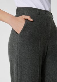 Pantalons en laine gris à taille haute, avec fermeture à bouton et poches latérales, dotés d'une texture douce et d'un design coupe droite.