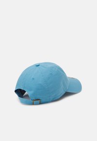 Light blue baseball cap with a curved brim, fabric texture, adjustable strap at the back, and ventilation eyelets on the sides.