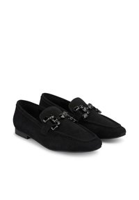 Mocassini in suede neri con design a punta, dotati di una fibbia decorativa in pietra nera sul davanti e tacco basso e piatto.