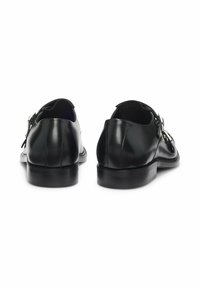 Schwarze Lederschuhe mit abgerundetem Zehenbereich, schlankem Design und niedrigem Absatz. Verfügen über doppelte Schnallen seitlich. Glatte Textur.