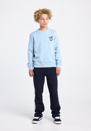 Light blue sweatshirt with "RAMEN CLUB" graphic, paired with dark navy pants featuring white side stripes, and black sneakers.
