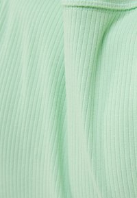 Tissu à rayures vert clair montrant des détails texturés, avec des lignes horizontales et une qualité douce et extensible. Vue rapprochée du matériau.