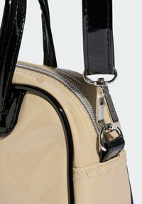 Beige patent leather handbag with black glossy accents, silver zipper, and contrasting stitching. Features dual handles and a clip attachment.