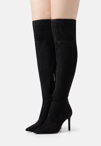 Svarta över-knästövlar i mocka, med spetsig tå, stilettklack och detaljer med siddragkedja. Slät textur med minimal sömnad.