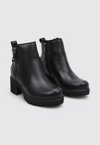 Botas de tobillo de cuero negro con un acabado suave, que presentan cremalleras laterales, un tacón cuadrado y suelas texturizadas para mayor agarre.