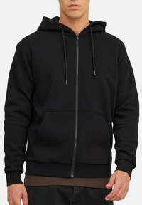 Haut de hoodie zippé noir en tissu mélangé de coton. Caractéristiques : poches avant, cordons de serrage ajustables et design à coupe décontractée.
