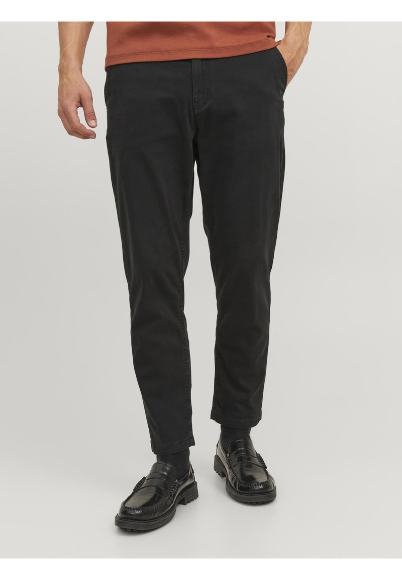 Pantaloni neri in cotone con vestibilità slim, dotati di tasche anteriori, una texture liscia e abbinati a mocassini neri lucidi.