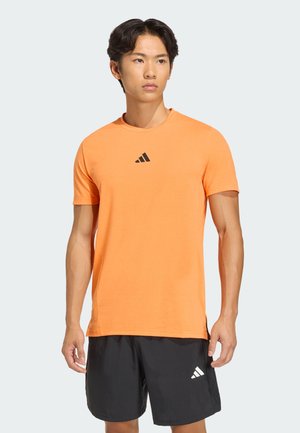 Orange short-sleeve athletic t-shirt with a round neckline and black Adidas logo on the chest, made from a lightweight, smooth fabric.