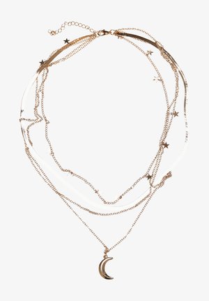 Zlato barvana plastena ogrlica s povezovanimi verigami, okrašena s zvezdnimi dodatki in mesecnim obeskom, ki združuje kovinske in vrvne materiale.