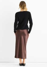 Black long-sleeve sweater made of fine knit fabric, paired with a brown satin, ankle-length skirt. Smooth texture with a slight sheen.
