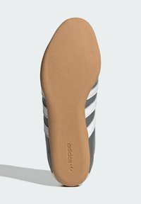 Σόλα αθλητικού παπουτσιού σε γκρι χρώμα με υφή από ανοιχτό καφέ καουτσούκ. Διαθέτει τρεις λευκές ρίγες και το λογότυπο "adidas" ανάγλυφο στην πλευρά.