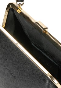 Czarna skórzana kopertówka o teksturowanej powierzchni, złotą metalową ramką i zapięciem. Wewnątrz znajduje się czarna tkaninowa podszewka z kieszonką na zamek.