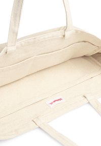 Borsa tote in tela beige con due manici resistenti, caratterizzata da un ampio interno e un piccolo etichetta del marchio all'interno. Senza motivi visibili.