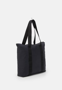 Mustasta nylonnistasta olkalaukusta, jossa on kaksi mustaa hihnaa, suorakulmainen muoto, pehmustettu pinta ja yläosassa vetoketjukiinnitys turvallista pääsyä varten.