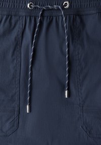 Shorts bleu marine en tissu texturé, avec une taille élastique et un cordon de serrage avec des détails en métal argenté et des accents blancs. Inclus des poches latérales.